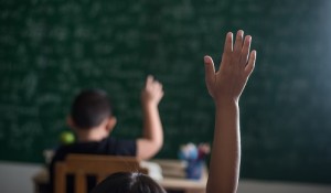 kid raising his hand in classroom