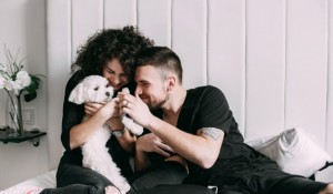 man-woman-black-play-with-little-white-dog-bed_1304-3280