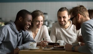 millennial-girl-showing-funny-mobile-video-friends-cafe_1163-5148